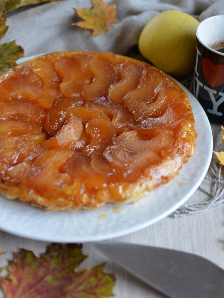 Tarte tatin aux pommes caramélisées avec une tasse de café, une pomme, des feuilles d'automne et une écharpe