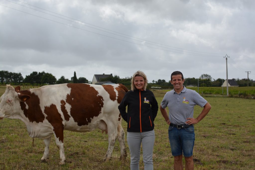 Une femme et un homme posent devant un vache de leur ferme