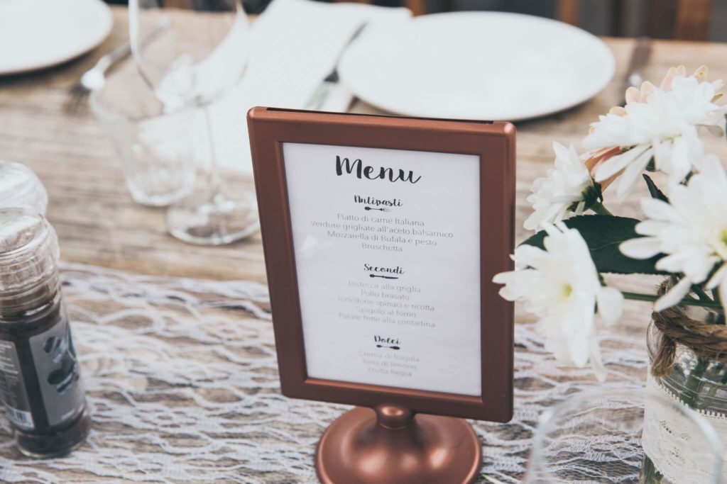 Menu affiché dans un petit cadre sur une table préparée pour un repas