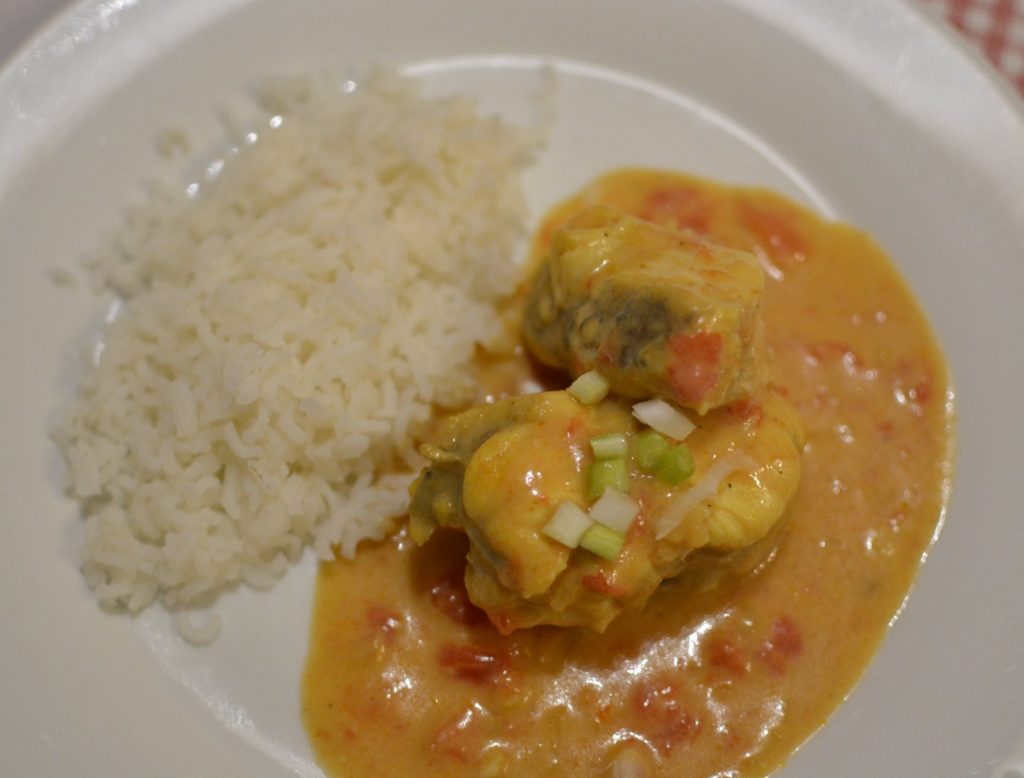 Assiette avec du riz blanc et des moreceaux de lotte sauce au curry