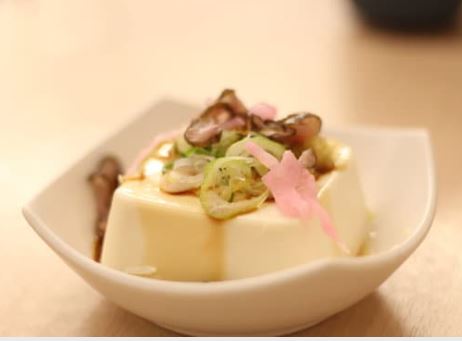 Tofu soyeux blanc dans un petit ramequin avec des fruits et une sauce caramel