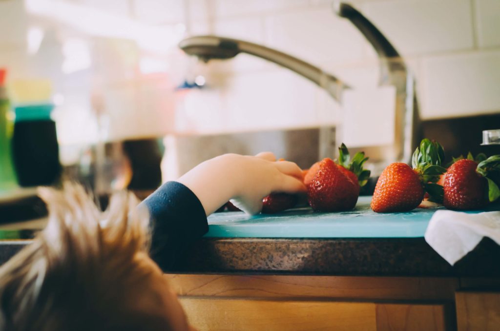 Main d'enfant attrapant une fraise sur un plan de travail