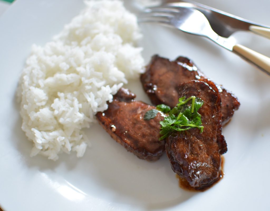 Tranche de viande dans une sauce brune avec du riz dans une assiette blanche