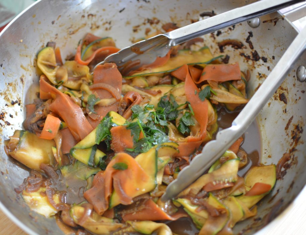 Courgettes et carottes émincées dans une poêle avec une sauce brune