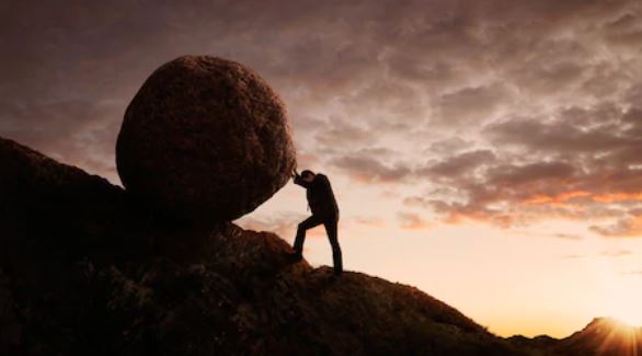 Homme sur une montagne poussant un rocher rond