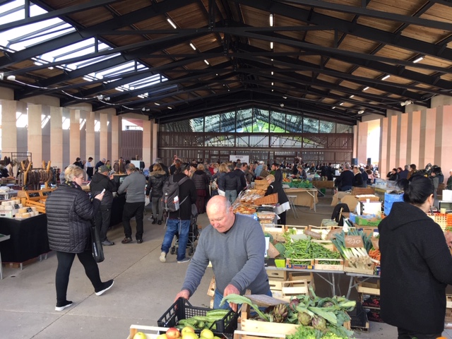 Marché couvert avec des gens qui achètent des légumes