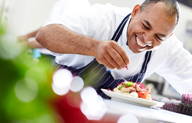 Homme souriant avec un tablier à rayure déposant des fleurs sur une assiette de nourriture