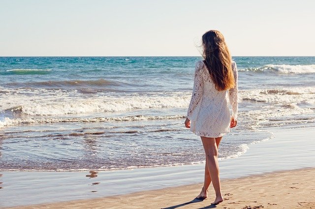 femme pieds nus au bord de l'eau sur une plage